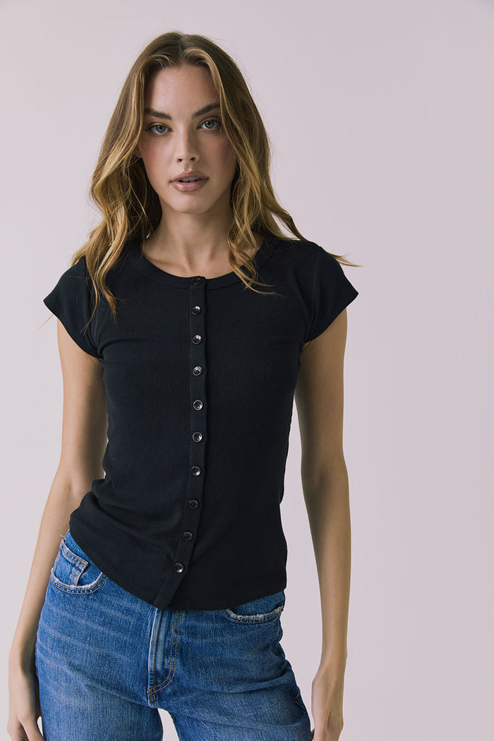 Front view of a woman wearing the Chaser Anchor Black Tee with buttons and blue jeans against a plain background