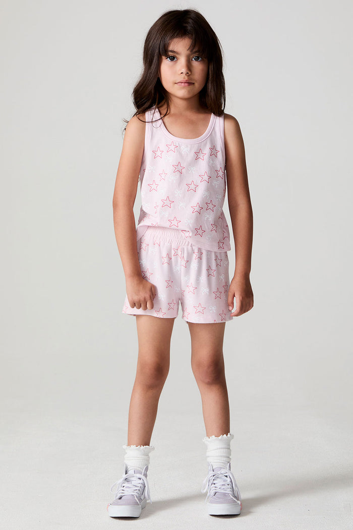 Front view of a girl wearing the Chaser Bows and Stars Shorts and white sneakers on a neutral background