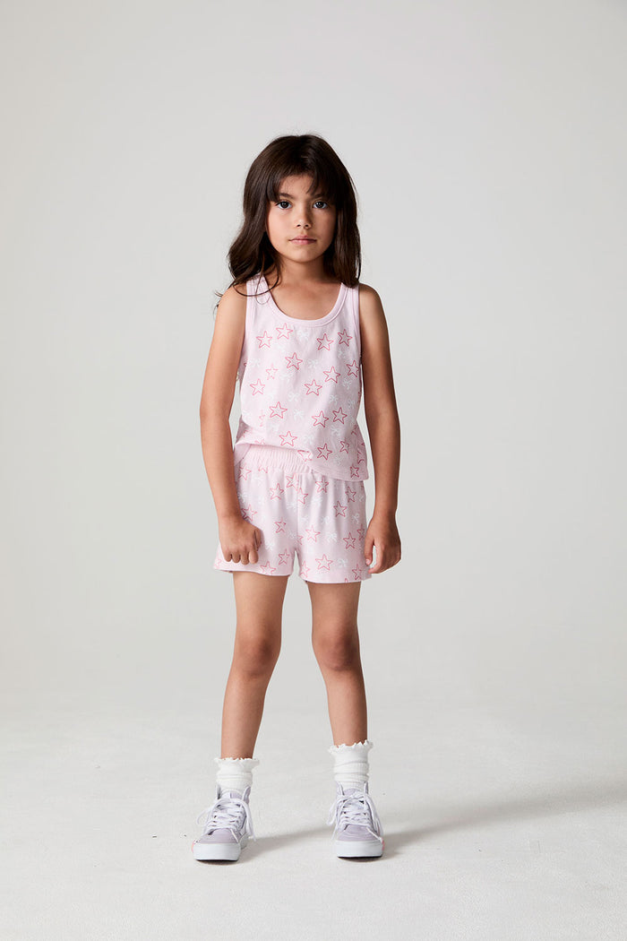 Front view of a girl wearing the Chaser Bows and Stars Shorts and sneakers on a neutral background