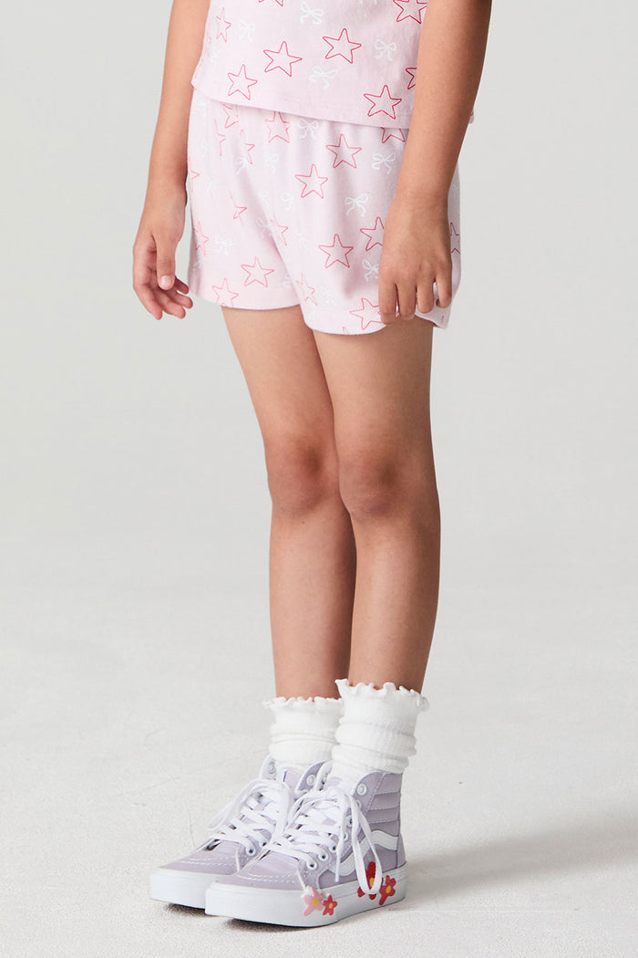 Side angle view of a girl wearing the Chaser Bows and Stars Shorts and top on a neutral background