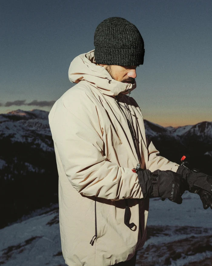 Side view of Cozy Marled Beanie in heathered charcoal showcasing rib knit texture and snug fit on model with snowy mountain background