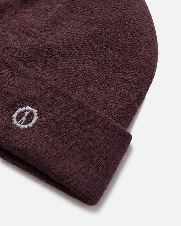 Close-up of cuffed beanie showing rib-knit alpaca wool and small embroidered PAKA logo on folded cuff against white background