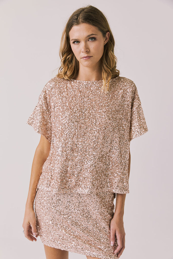 Front view of woman wearing Chaser’s Davis Bronze Brown Tee and matching Jayde Bronze Brown Mini Skirt on a light gray background