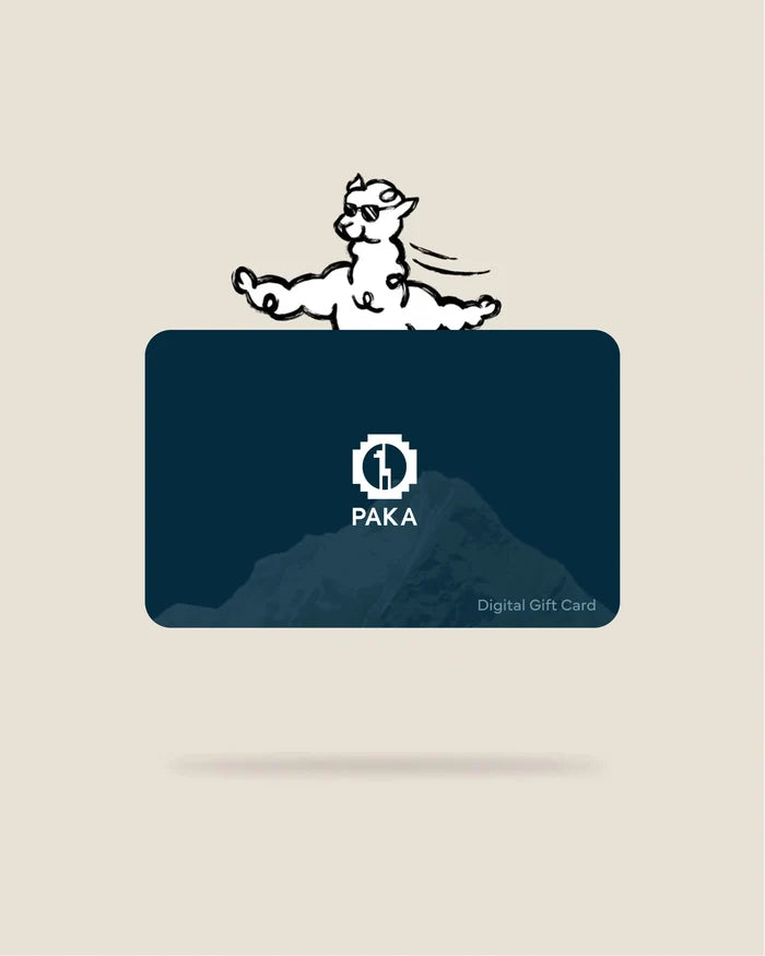 Front view of PAKA digital gift card showing white PAKA logo over a dark blue mountain graphic, ‘Digital Gift Card’ text, and a cartoon alpaca above on a beige background