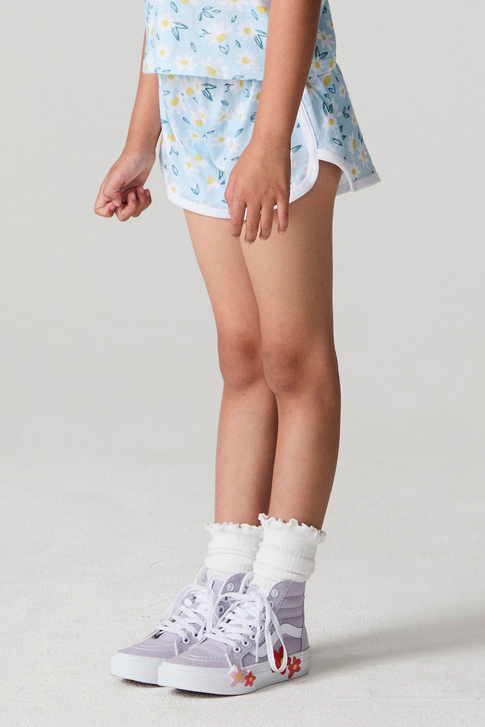 Side view of a girl wearing the Chaser Ditsy Daisies Shorts on a neutral background with arms lowered