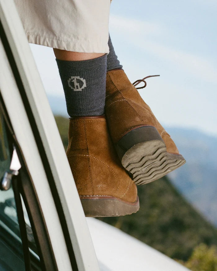 Close up of Essential Crew Socks in dark gray showing ribbed knit and PAKA logo, paired with brown suede boots