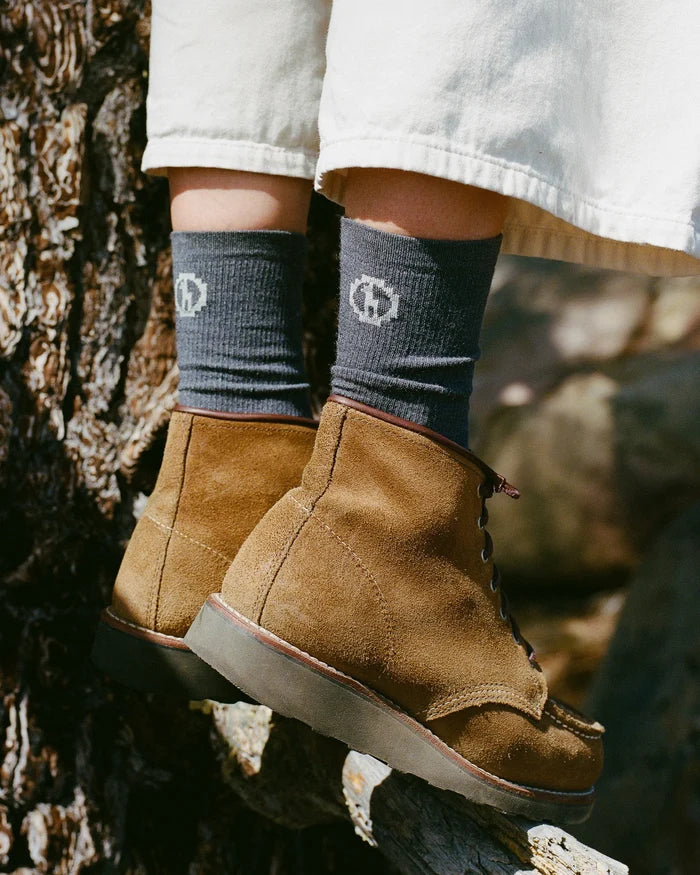 Side view of Essential Crew Socks in dark grey showing alpaca fabric and PAKA logo worn with brown suede boots outdoors