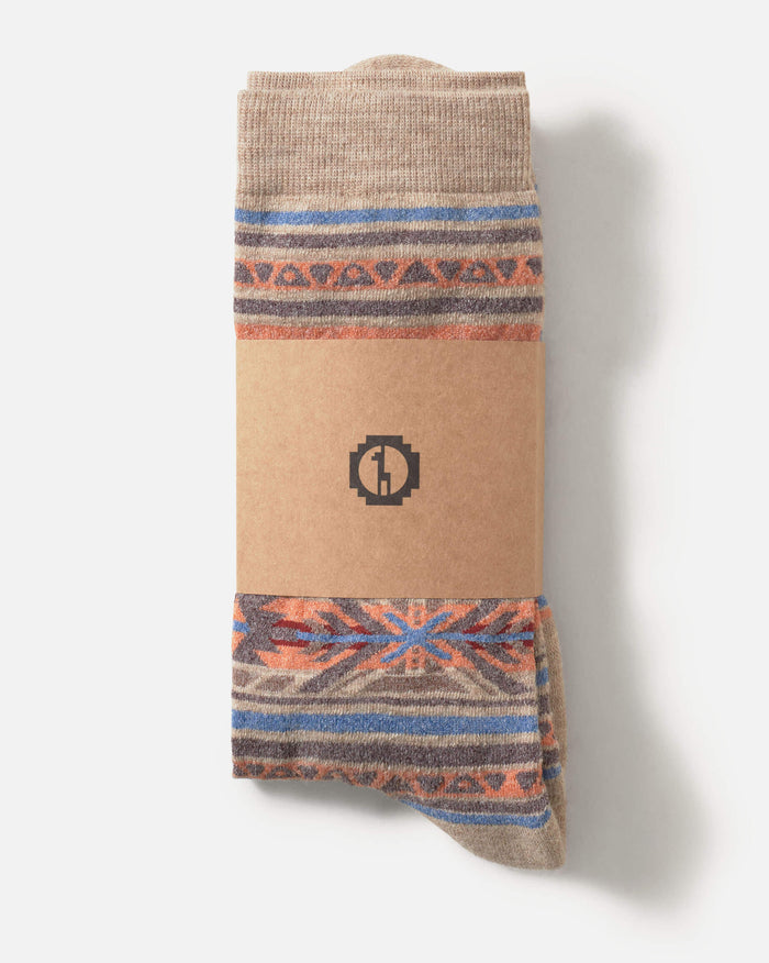 Top-down view of Inca crew socks showcasing tan geometric Inca pattern and kraft paper band with logo on white background