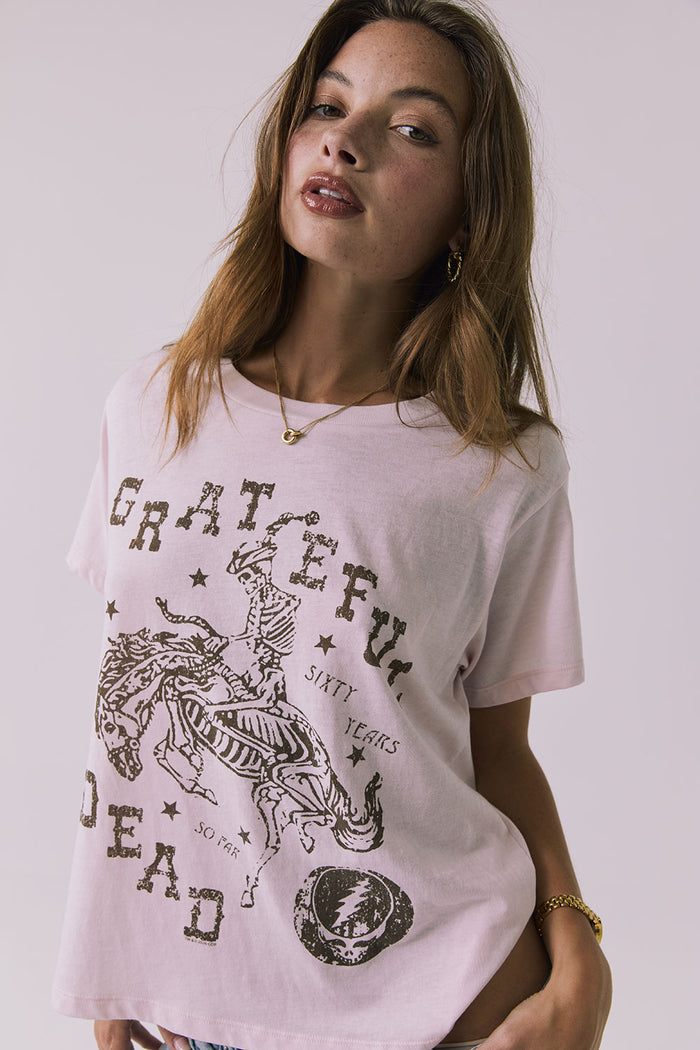 Side view of a woman wearing Chaser's the Grateful Dead 60 Years so Far pink tee with a graphic design on a plain background