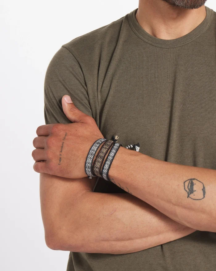 Closeup of forearms wearing Handwoven Quechua Bracelets (3-Pack) showing Inca pattern and braided tassels on white background