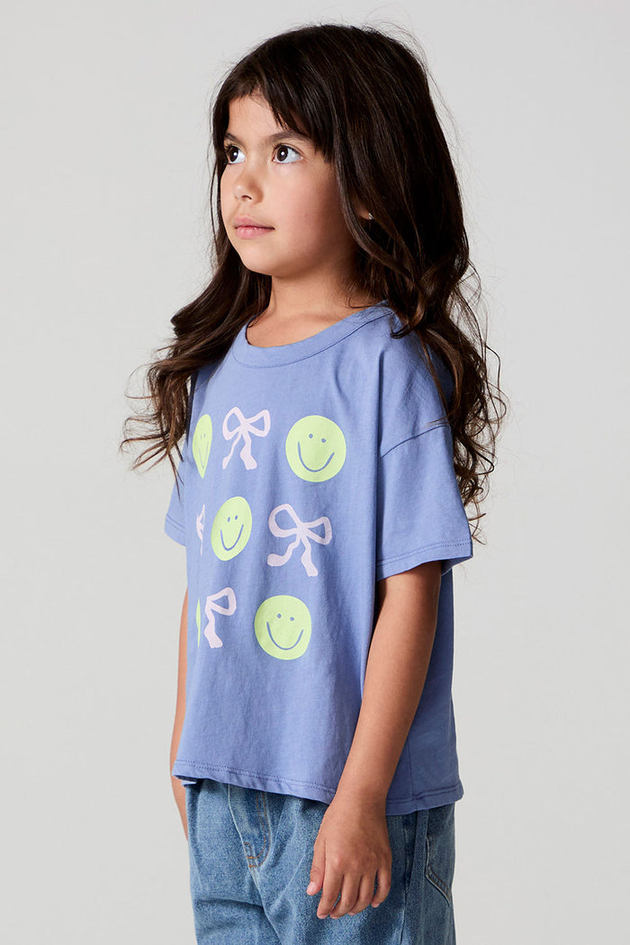 Side view of a girl wearing the Chaser Happy Bows Tee on a neutral background