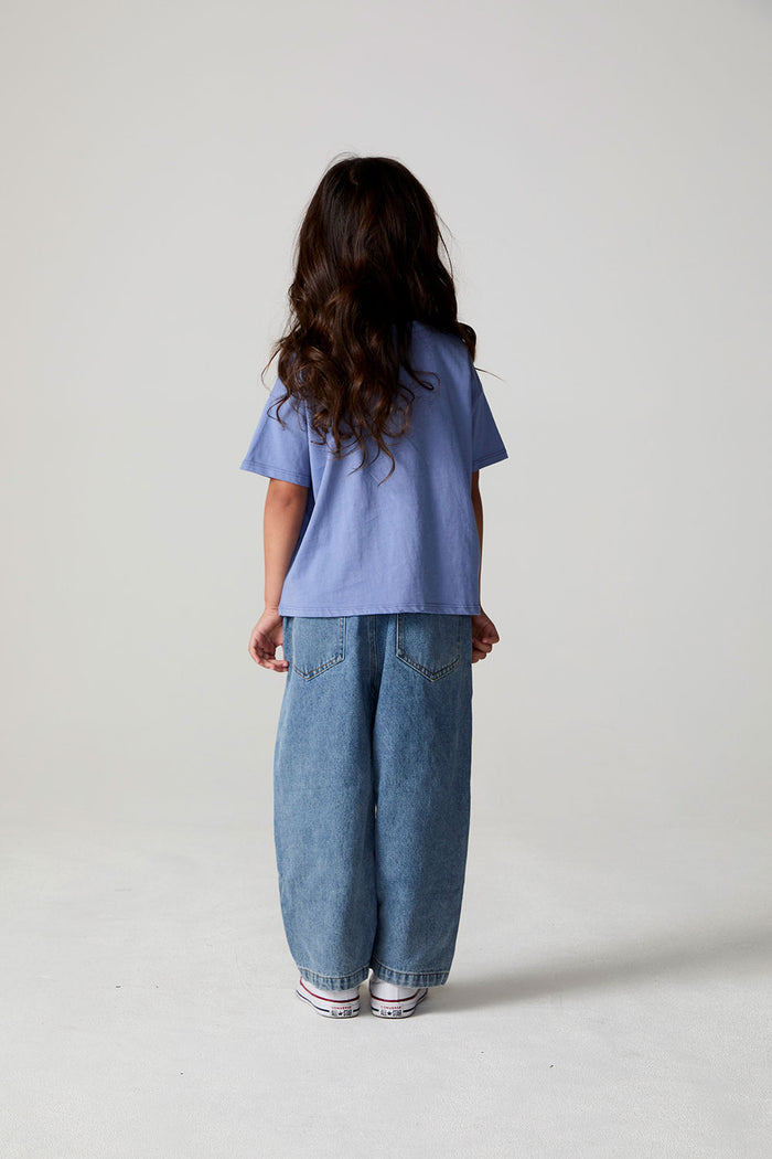 Full body back view of a girl wearing the Chaser Happy Bows Tee on a neutral background