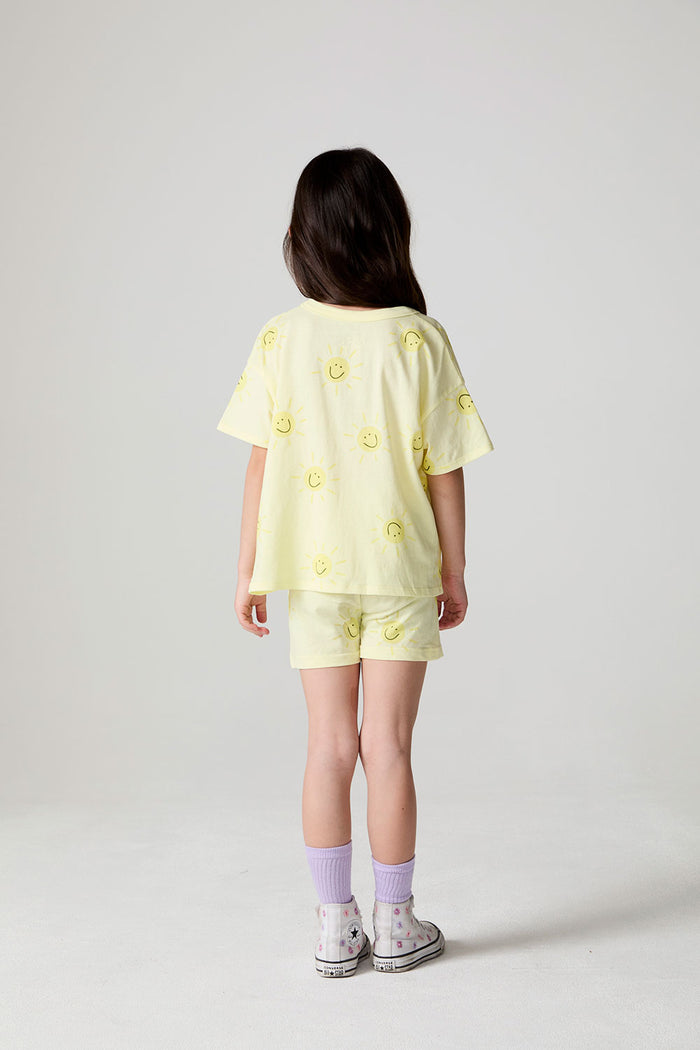 Back view of a girl wearing the Chaser Happy Happy Tee on a neutral background