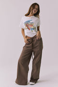 Full body view of the Chaser Layover Cognac Wash Jogger styled with Chaser's Tom Petty 1980 Tour white t-shirt and sneakers for an effortless laid-back look  on a plain background