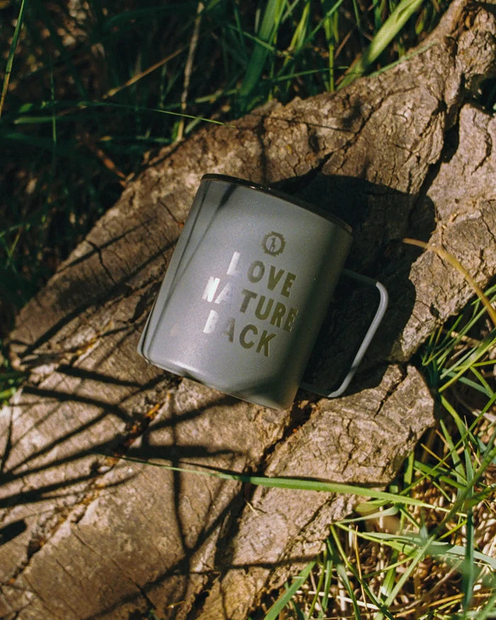 Mug with 'Love Nature Back' text on a stone surface with grass