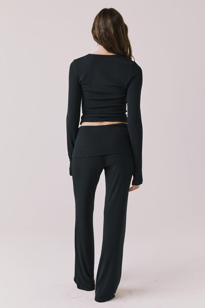 Full body back view of woman wearing Chaser’s True Black Mantra Legging with matching Porta True Black Long Sleeve on a plain background