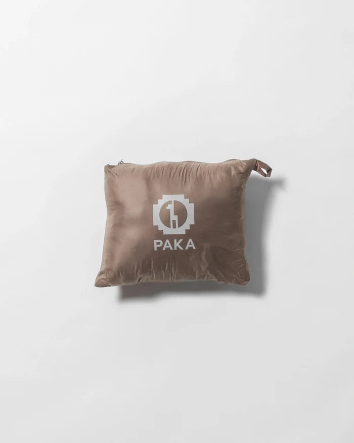 Top-down view of Men’s Mayu Ultralight Jacket packed into its Fossil tan stuff sack showcasing compact, packable design and PAKA logo on a white background