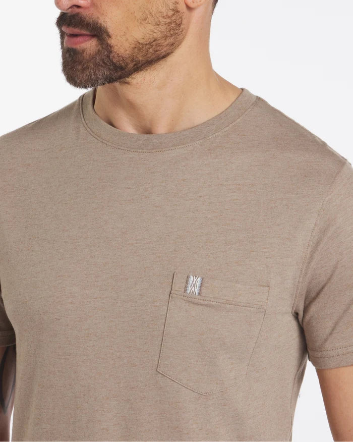 Close-up of Men’s Pocket Tee in cappuccino showcasing chest pocket with woven Inca tag and alpaca fabric on model against white background