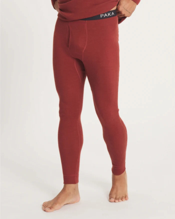 Front view of men’s alpaca thermal baselayer bottoms in clay red showing slim fit and elastic waistband on light background
