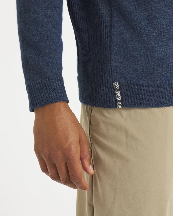 Close-up of navy men’s Ultralight alpaca crewneck showing ribbed hem, cuff, and woven side tag on a model wearing khaki pants