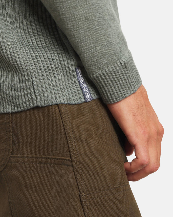 Close-up side view of Men’s Ultralight Crew in lichen showing ribbed hem, woven side tag, and sleeve cuff on model