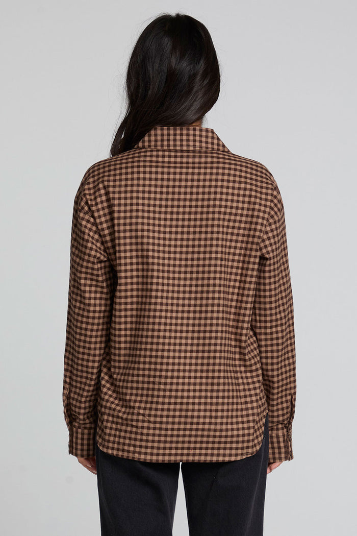 Back view of a woman wearing the Chaser Pine button down on a neutral background with arms down