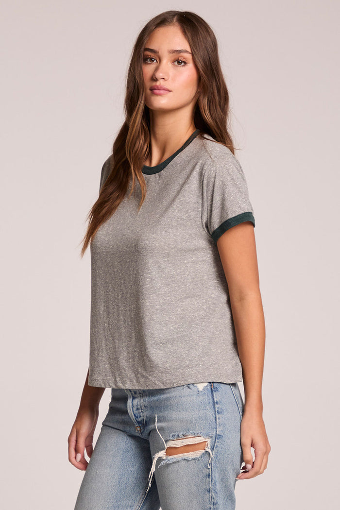 Side angle view of a woman wearing the Chaser  Rambler Streaky Grey and Pine Tee on a neutral background with arms at her sides