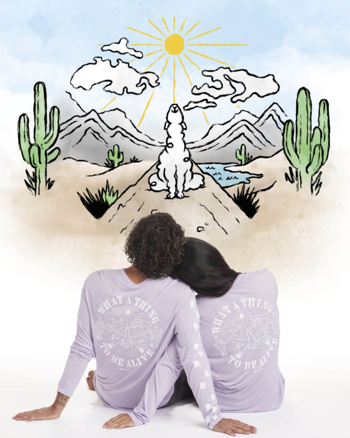 Back view of Sebastian Long Sleeve in lavender on two seated models, showing large alpaca graphic and paw-print sleeve details