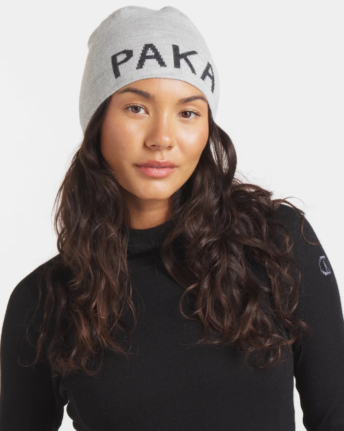Front view of Skull Cap Beanie on model showcasing jacquard PAKA logo on light grey knit with white background