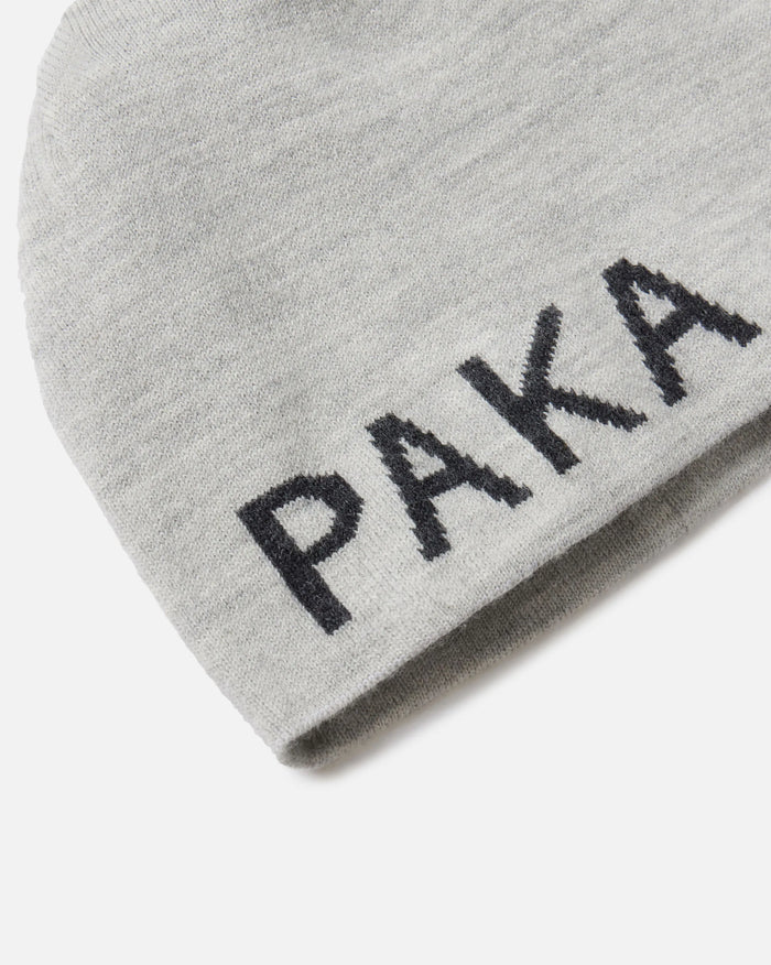 Close-up of light grey Skull Cap Beanie showing jacquard PAKA logo on folded cuff against white background