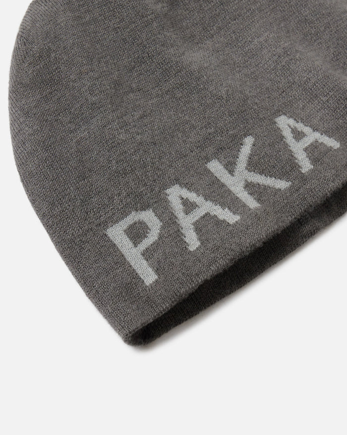 Close-up of skull cap beanie showcasing jacquard PAKA logo on gunmetal grey alpaca knit against white background