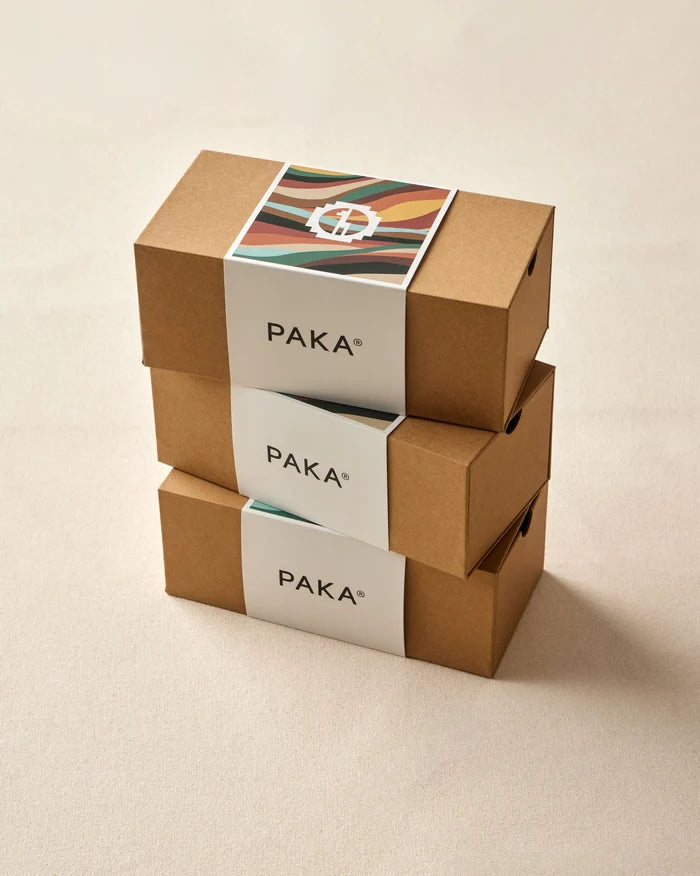Three-quarter view of Sock Gift Box with stacked PAKA kraft boxes and colorful lid art on beige background