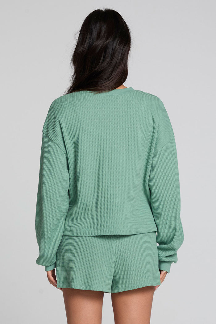 Back view of a woman wearing the Chaser  Suzzans Verdelle Sweatshirt on a neutral background with shorts