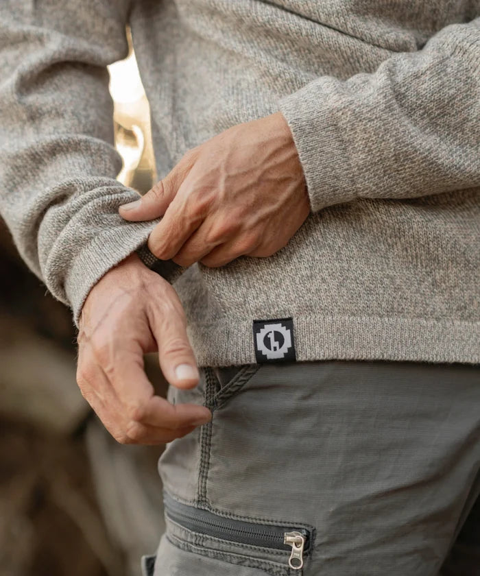 Close-up of The Cusco sweater in Timber showing marled alpaca-merino knit, ribbed hem and side brand tag worn by a model