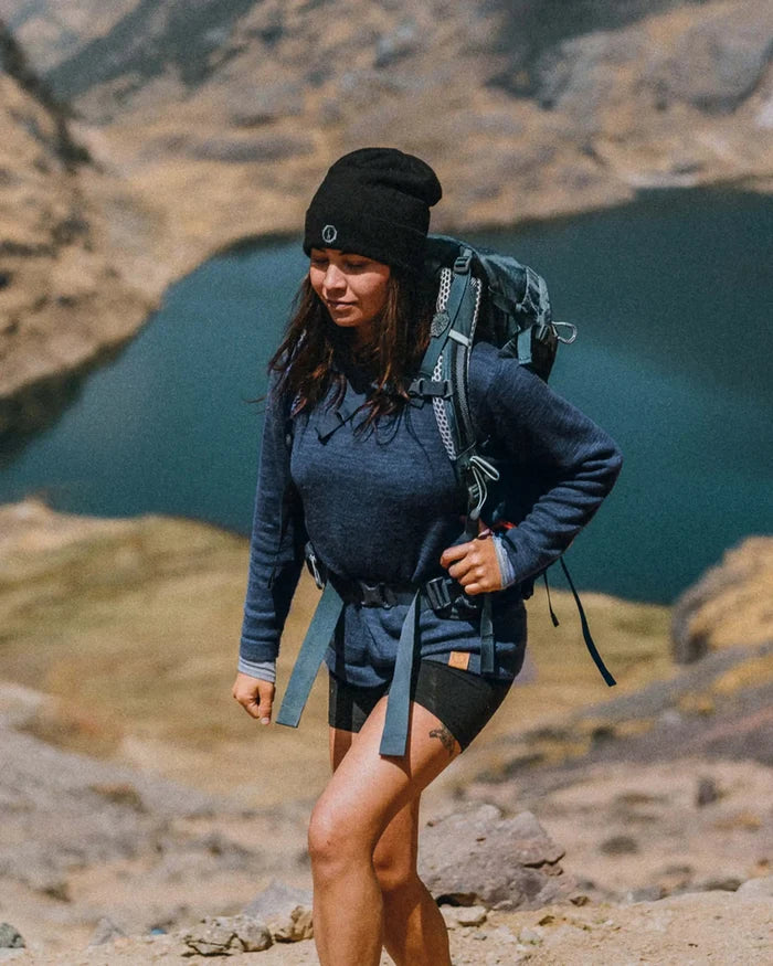 Front three-quarter view of The Original Crew alpaca crewneck in navy on a model, relaxed fit, long sleeves, rocky trail and mountain lake background