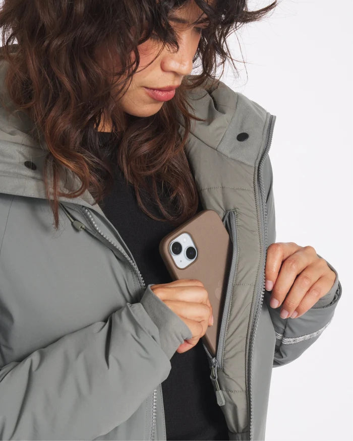 Close-up of Women’s Apu Parka showing inner zip chest pocket as model places phone on white background