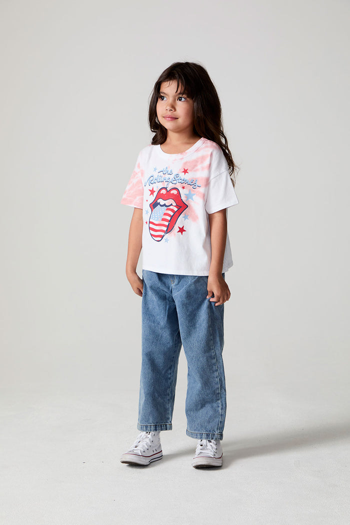 A full body side angle view of a girl wearing the Chaser The Rolling Stones Americana Stones Tee on a neutral background