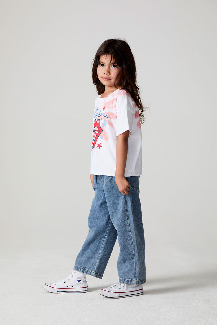 A full body side view of a girl wearing the Chaser The Rolling Stones Americana Stones Tee on a neutral background