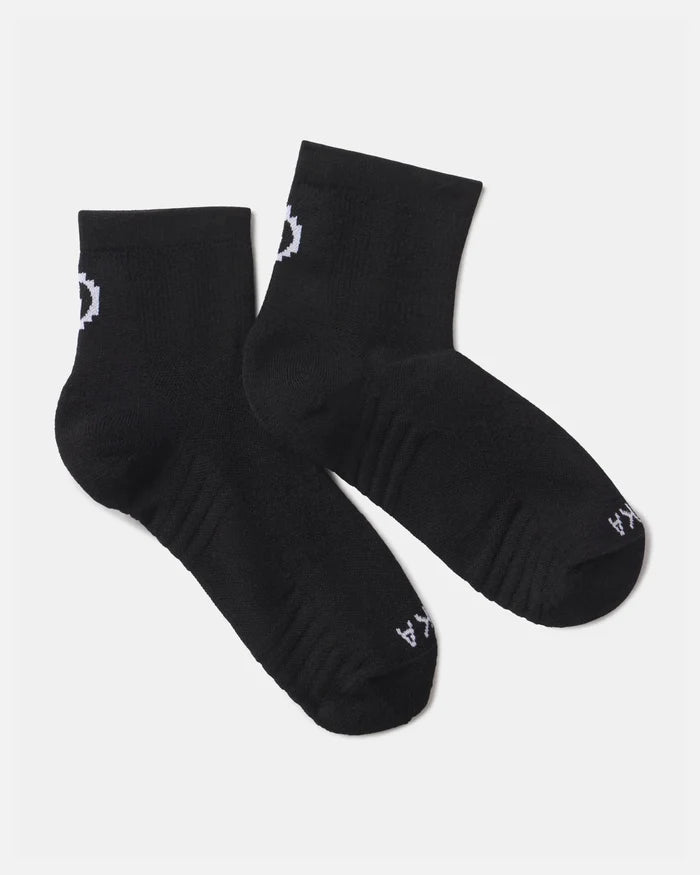 Flat lay of Trail 1/4 crew socks in black showcasing white PAKA logo and ribbed cushioned footbed on a light gray background