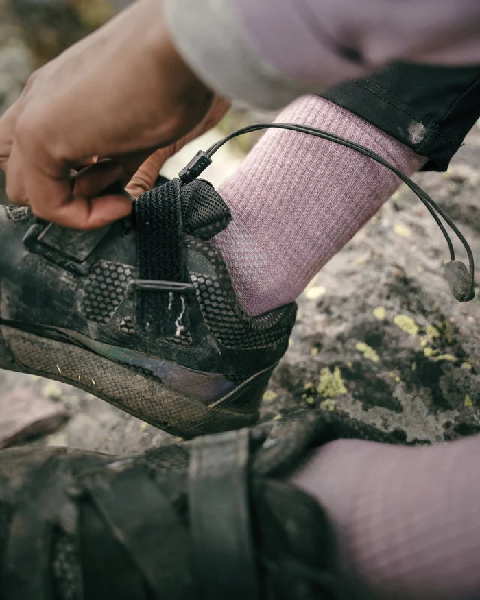 Close-up of Trail 3/4 crew sock in quail pink on foot showing ribbed knit and ankle fit with hiking shoe on rocky trail