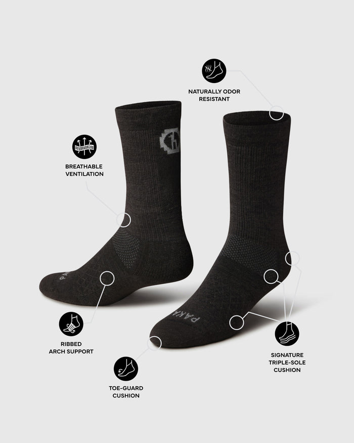Angled black Trail Crew hiking socks showing vented mesh, ribbed arch support, toe-guard and triple-sole cushion on gray