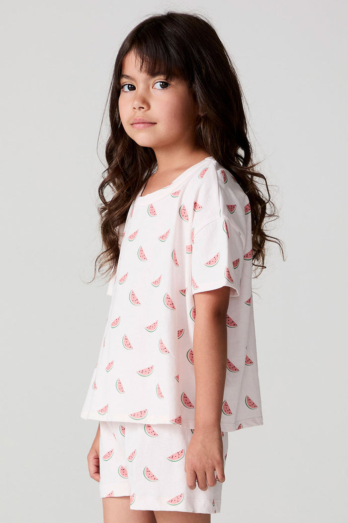 Side angle view of a girl wearing the Chaser Watermelon All Over Tee on a neutral background