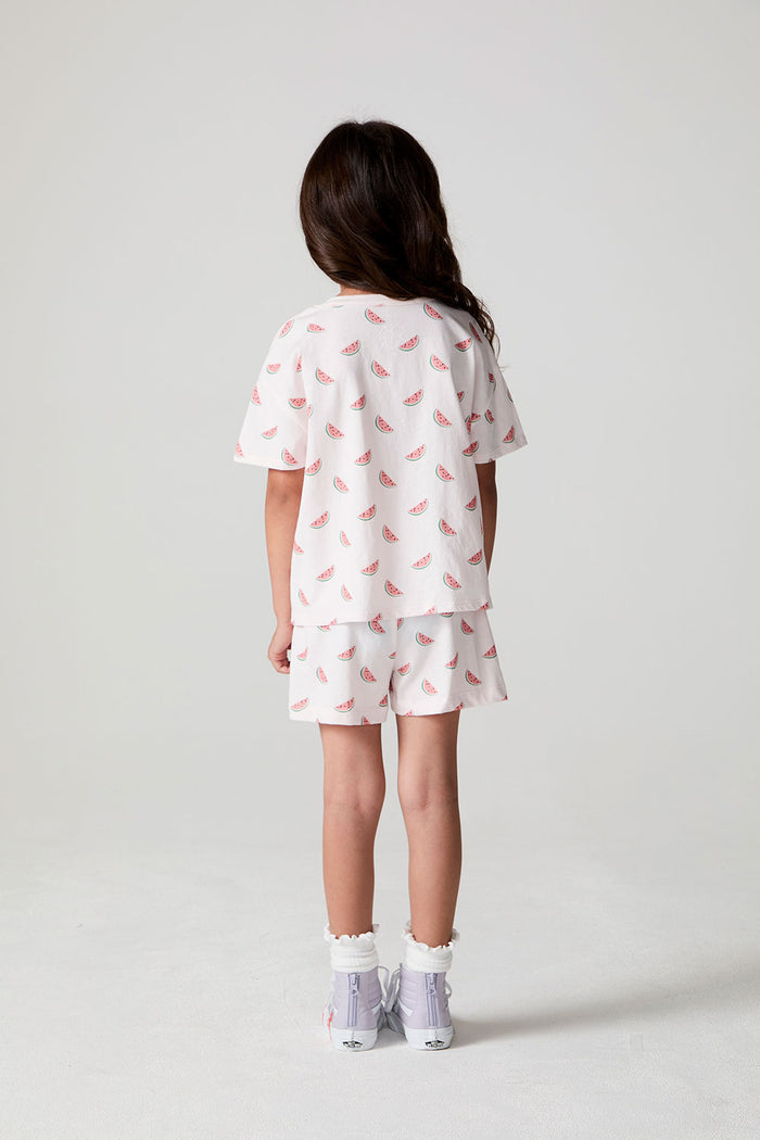 Full body back view of a girl wearing the Chaser Watermelon All Over Tee on a neutral background