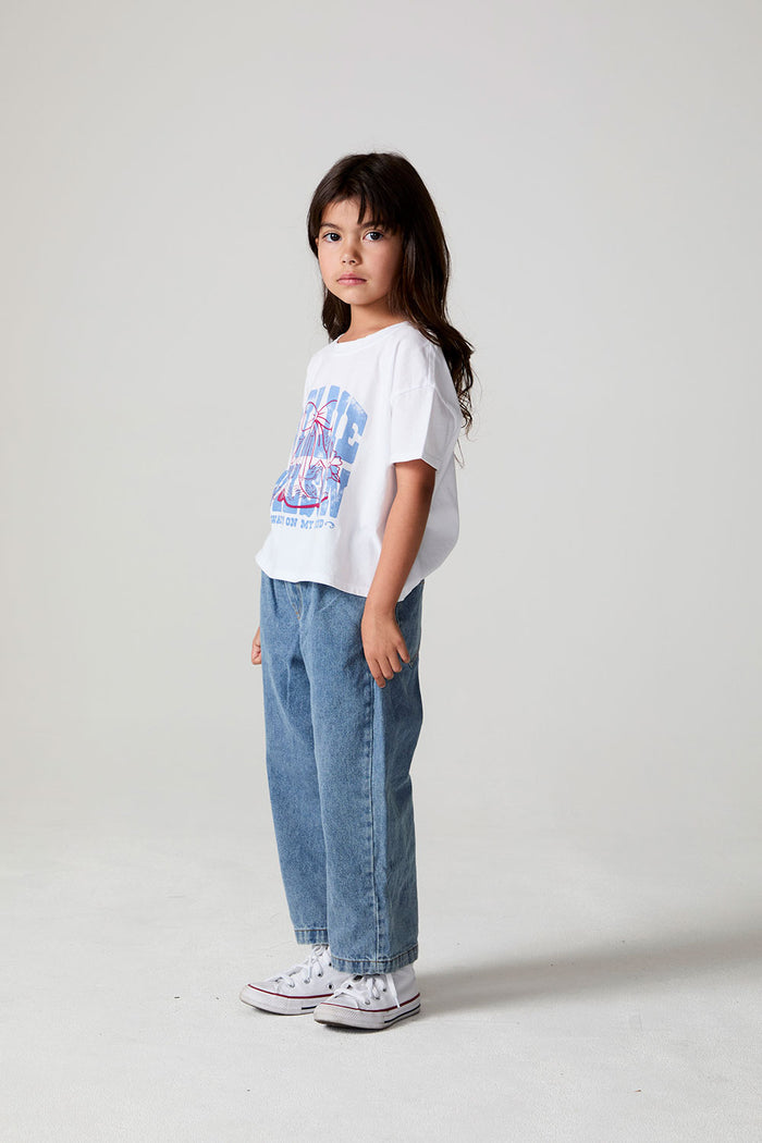 Full body side angle view of a girl wearing the Chaser Willie Nelson Cowgirl Tee on a neutral background