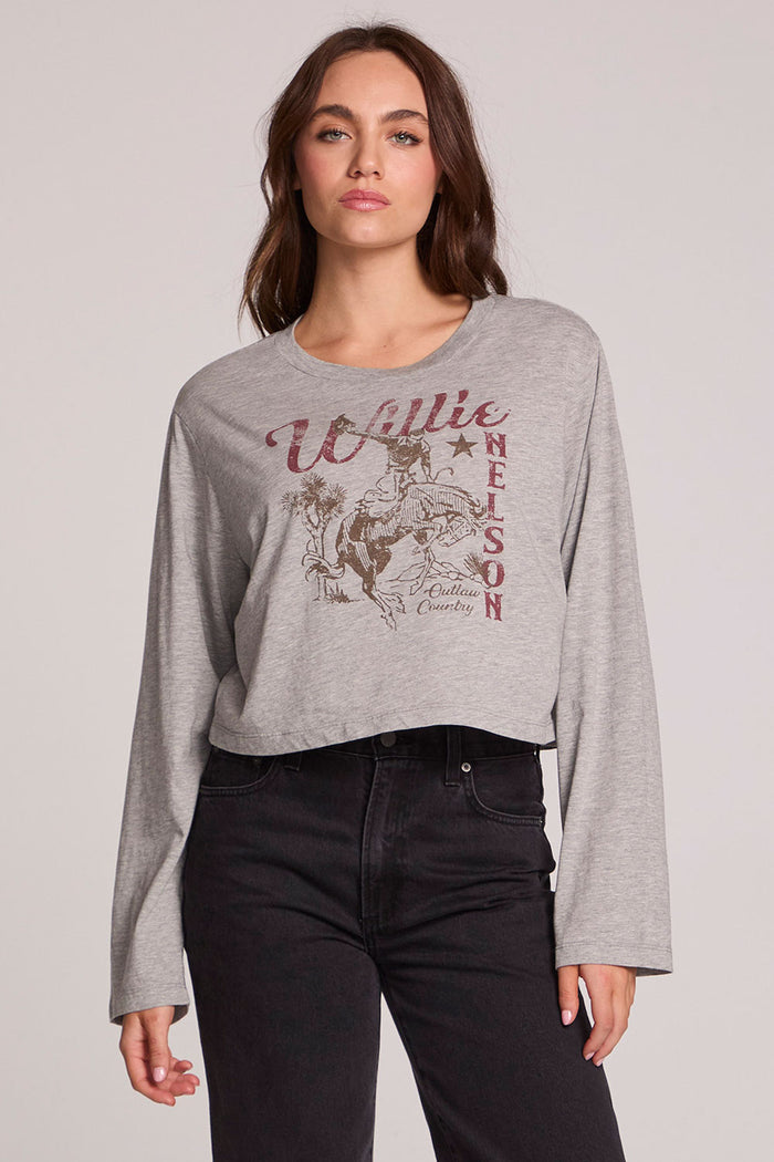 Front view of a woman wearing the Chaser Willie Nelson Horseback Long Sleeve on a neutral background with arms at sides and black pants
