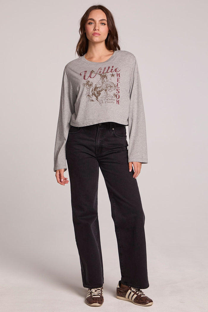 A full body front view of a woman wearing the Chaser Willie Nelson Horseback Long Sleeve on a neutral background