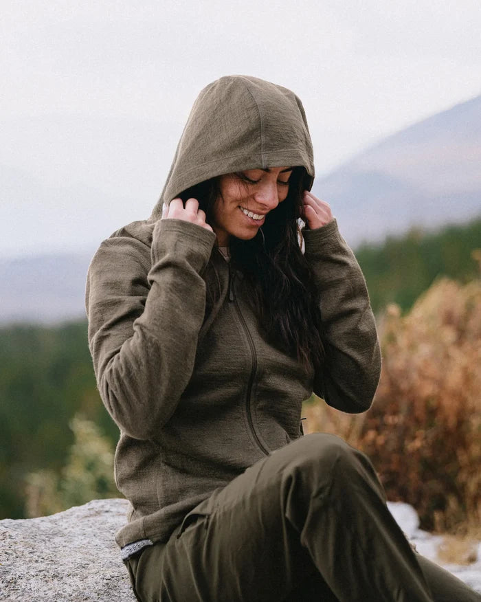 Three-quarter view of Women’s Breathe Full Zip alpaca hoodie in Andean Moss on seated model, zip front and hood