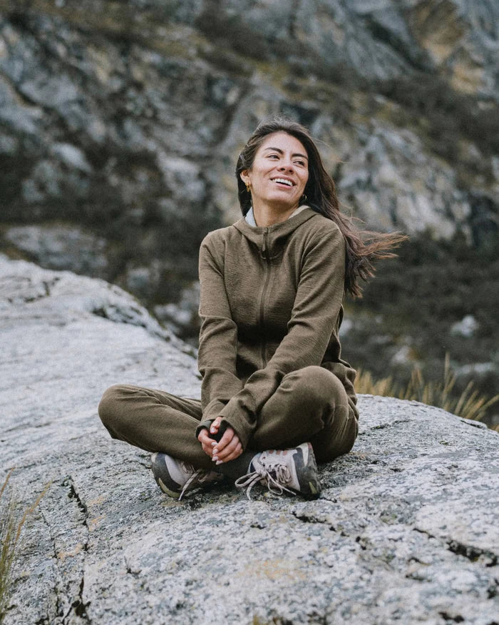 Front view of Women’s Breathe Full Zip Hoodie in Andean Moss with full zip, hood, breathable alpaca on rocky background