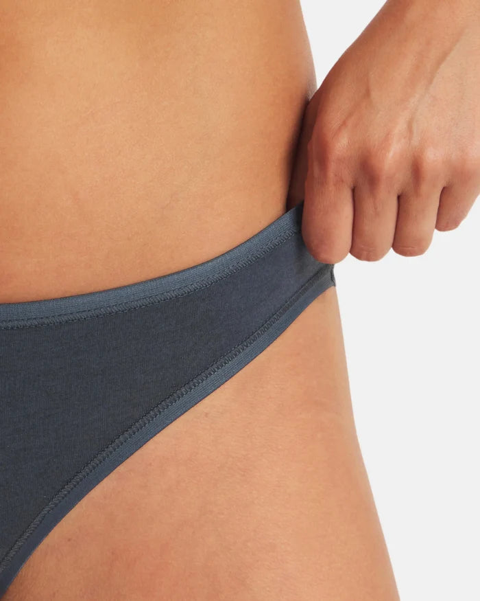 Close-up side view of Women’s Essential Bikini Brief in navy showing low-rise waistband on model against white