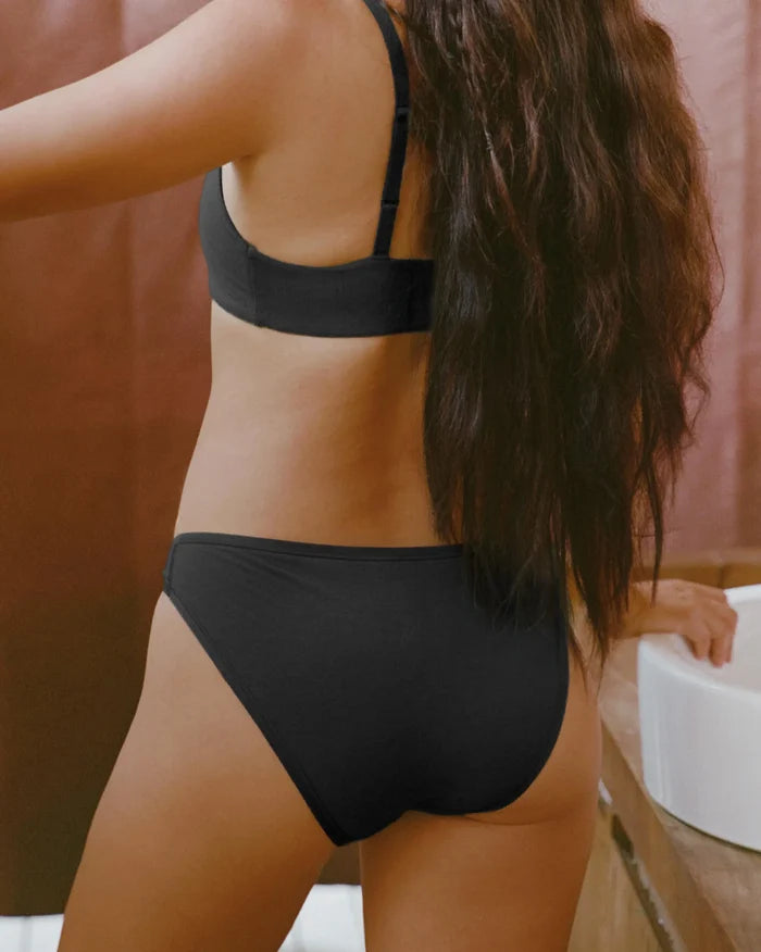 Rear view of Women’s Essential Bikini Brief showing low-profile cut and full back coverage on model in bathroom